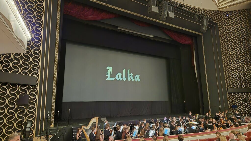 Ekran z tytułem filmu Lalka i orkiestra w Sali Moniuszki Teatru Wielkiego w Warszawie