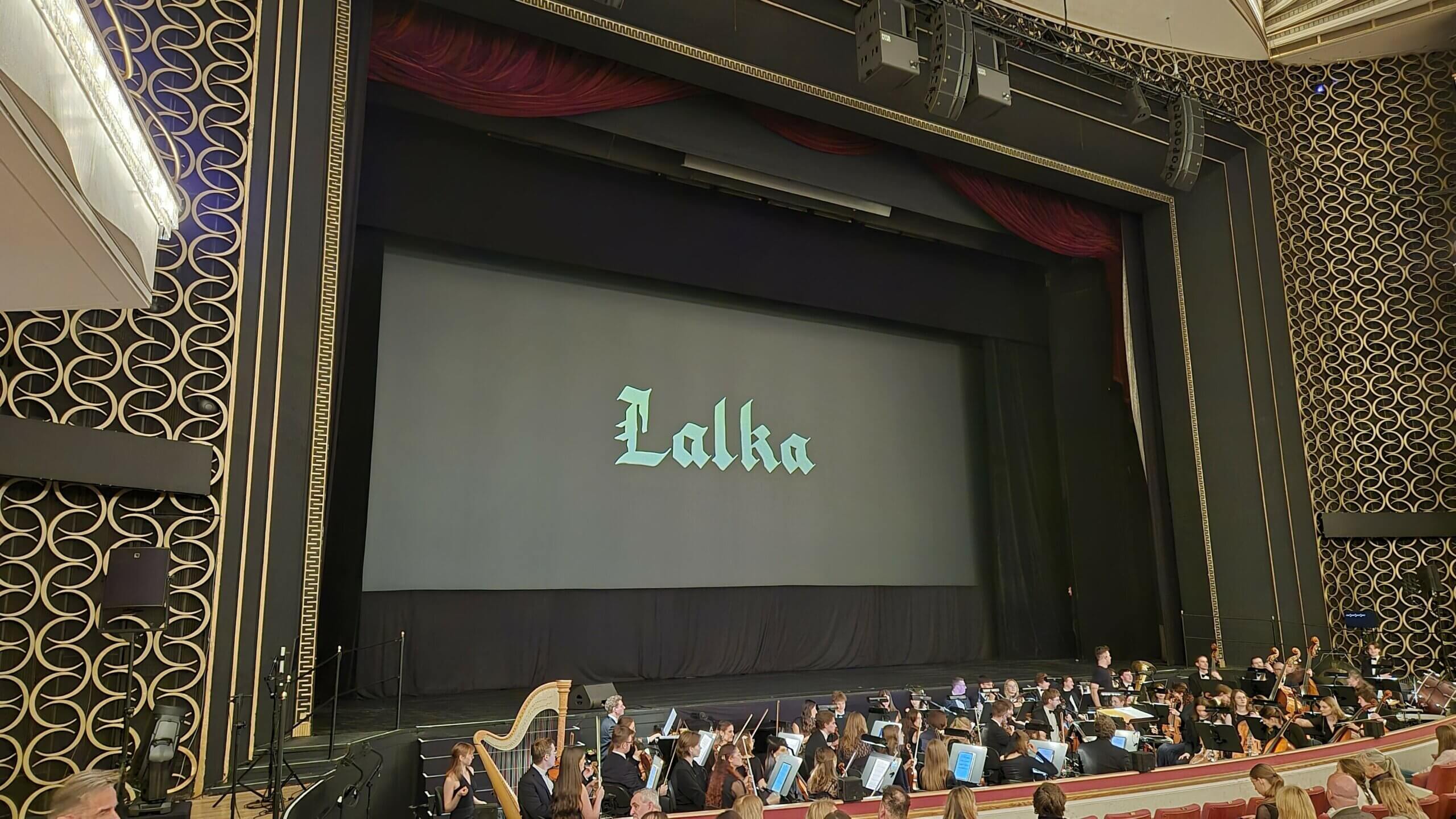 Ekran z tytułem filmu Lalka i orkiestra w Sali Moniuszki Teatru Wielkiego w Warszawie